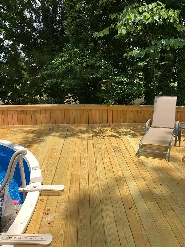 A sunny section of the wooden deck next to the pool, featuring a relaxing lounge chair.